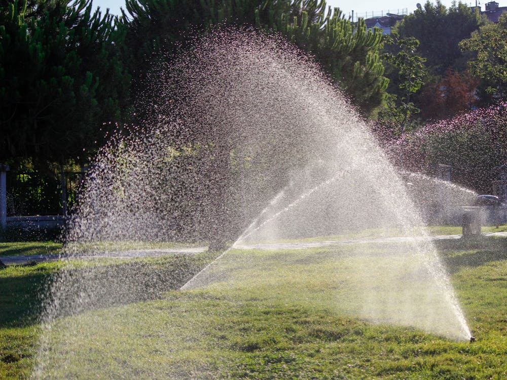 Automated sprinkler zones hydrating green turf in a commercial plaza. Call Honeycutt Landscaping Inc. to improve your commercial landscaping with smart irrigation solutions.
